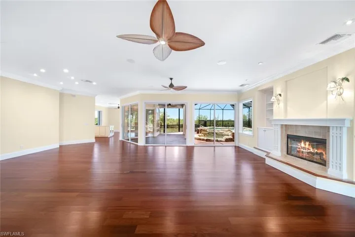 Unfurnished living room with a tile fireplace, crown molding, dark hardwood / wood-style floors, and ceiling fan
