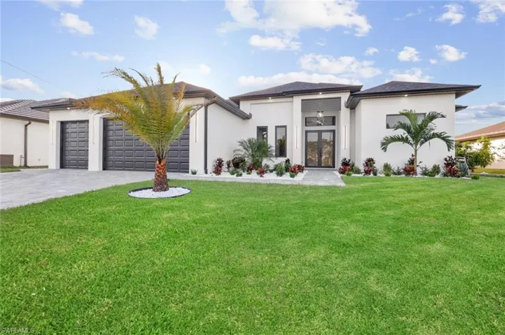 View of front of property featuring french doors, a front yard, and a garage