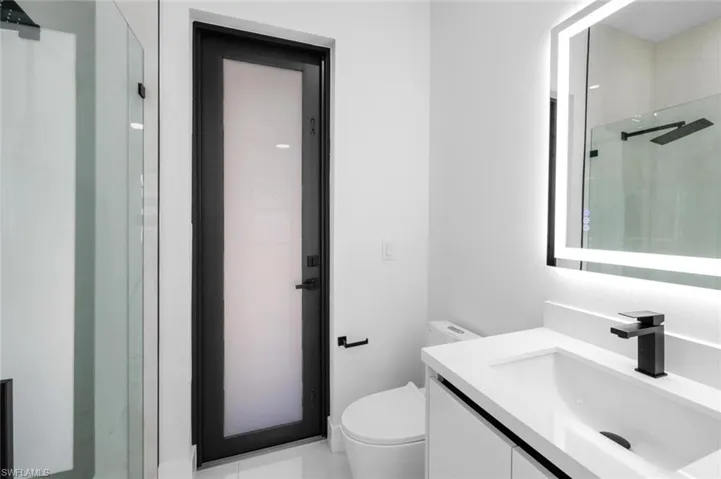 Bathroom with vanity, toilet, and a shower with shower door