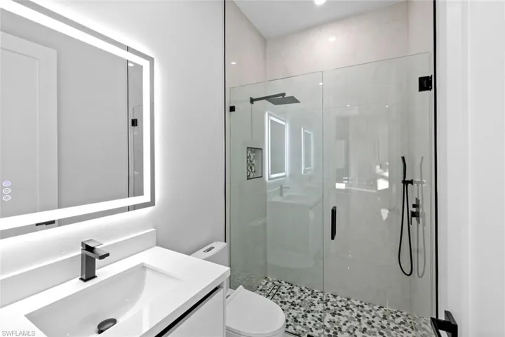 Bathroom featuring vanity, an enclosed shower, and toilet