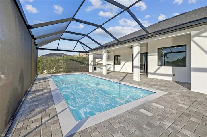 View of swimming pool featuring glass enclosure, ceiling fan, and a patio
