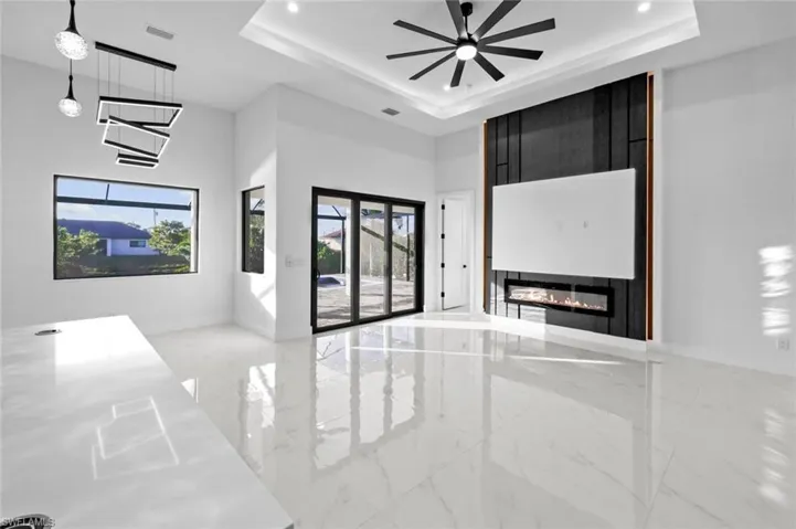 Unfurnished living room with a raised ceiling and ceiling fan