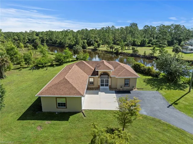 Exterior featuring a natural body of water, mature trees, a paved driveway, and an attached garage