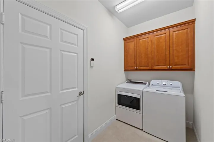 Laundry area featuring wood-finish cabinetry, and tiled flooring