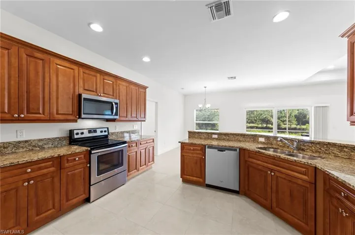 Kitchen featuring wood cabinetry, granite countertops, stainless steel appliances, and tile flooring