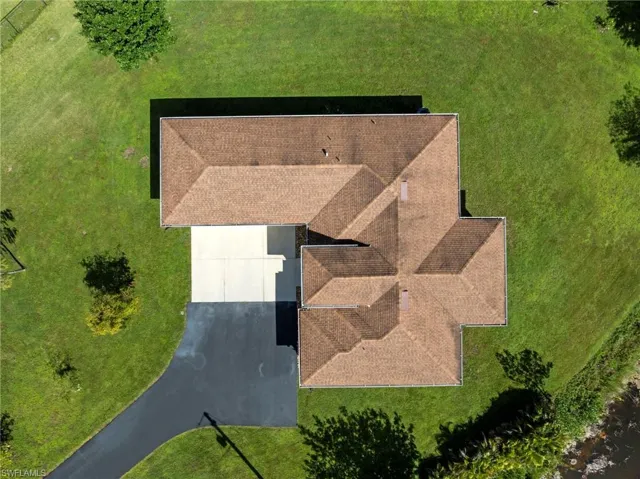 Expansive green lawn surrounds the property with a brown shingle roof