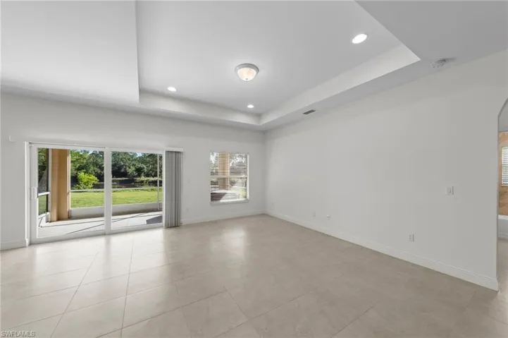 Recessed lighting, tray ceiling, tile flooring, sliding glass doors, and a screened patio