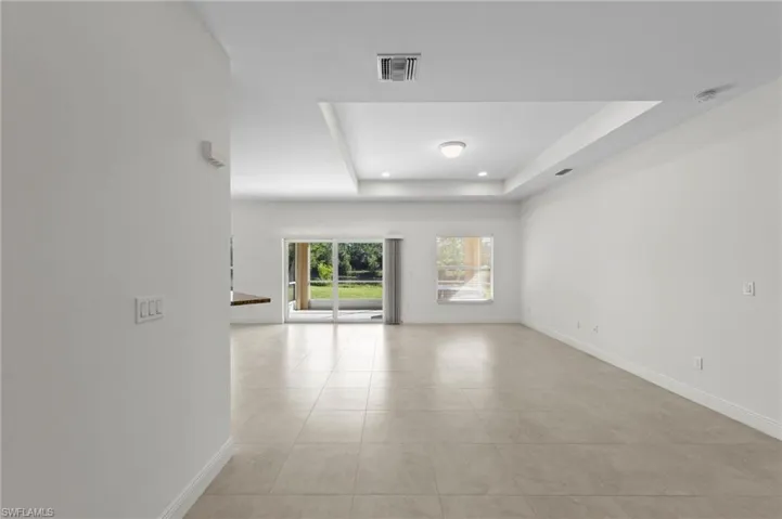 Recessed lighting, tray ceiling, tile flooring, sliding glass doors, and a built-in bar