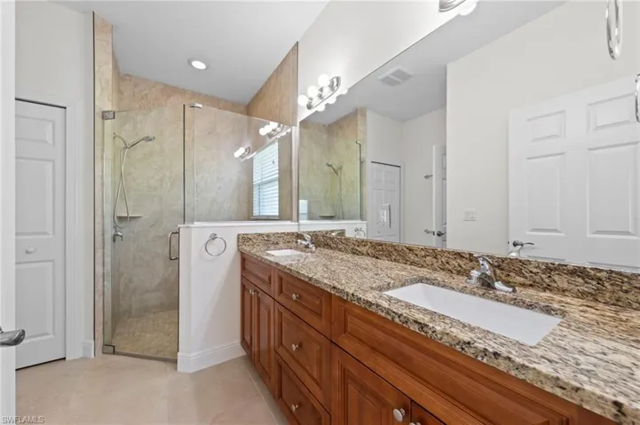 Dual vanity with granite countertop, wood-finish cabinetry, and undermount sinks