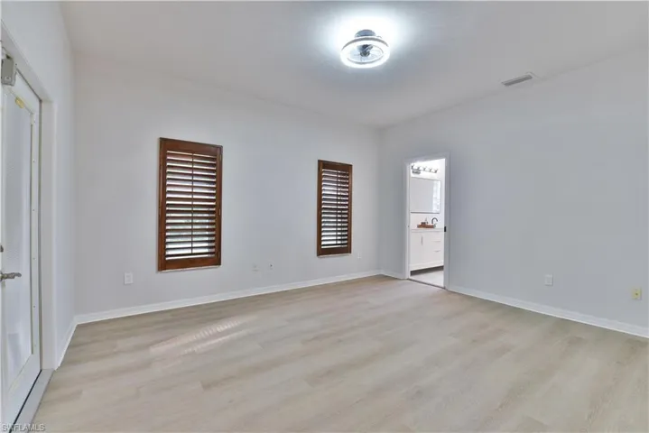 Empty room featuring light wood finished floors, visible vents, and a healthy amount of sunlight