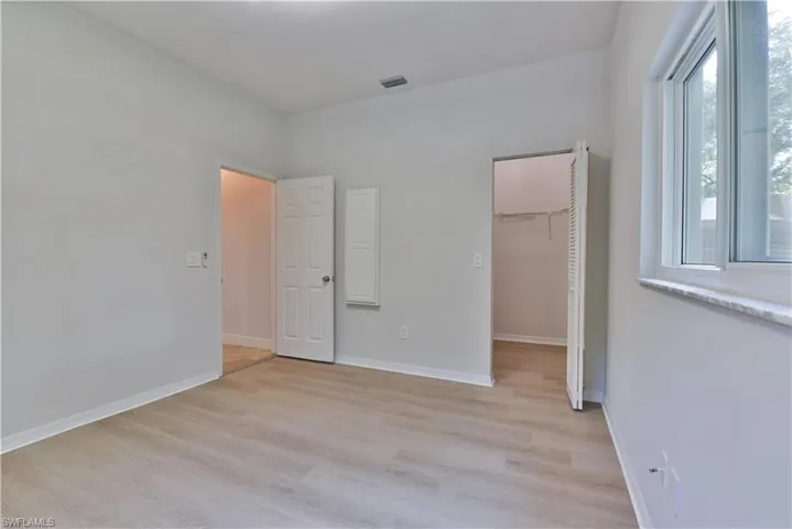 Unfurnished bedroom featuring light wood-style flooring, a closet, a spacious closet, visible vents, and baseboards