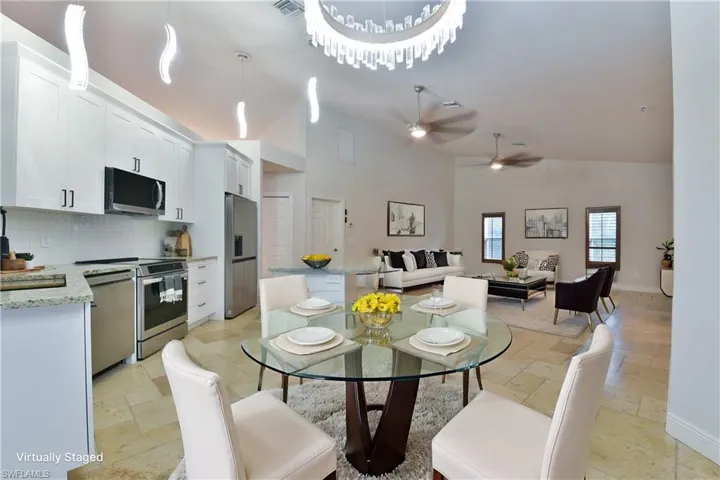 Dining room with visible vents, high vaulted ceiling, ceiling fan, and stone tile flooring