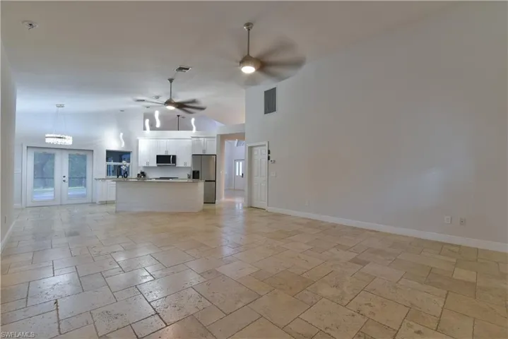 Unfurnished living room with high vaulted ceiling, visible vents, and stone tile floors