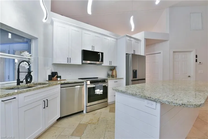 Kitchen featuring tasteful backsplash, white cabinetry, a center island, appliances with stainless steel finishes, and a sink