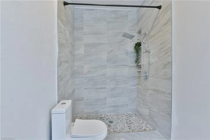 Full bathroom with a tile shower and toilet