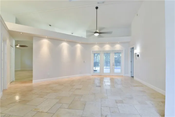 Spare room with high vaulted ceiling, stone tile floors, baseboards, and ceiling fan