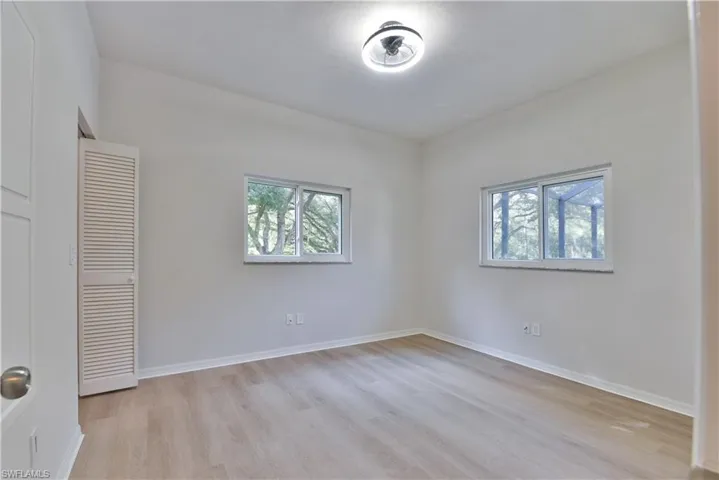 Unfurnished bedroom featuring light wood-type flooring, multiple windows, and baseboards