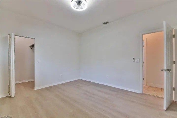Unfurnished bedroom featuring a spacious closet, light wood-style floors, baseboards, and visible vents