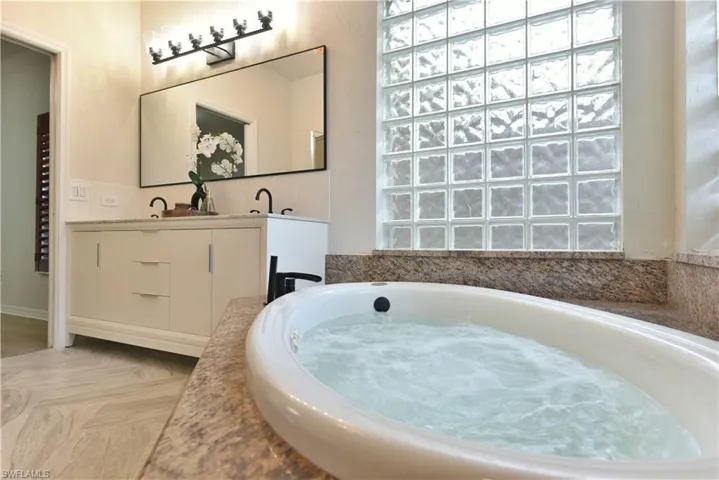 Bathroom with a bath, vanity, and a wealth of natural light