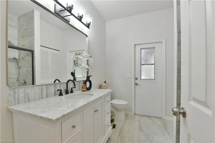 Full bath with vanity, baseboards, an enclosed shower, toilet, and marble finish floor
