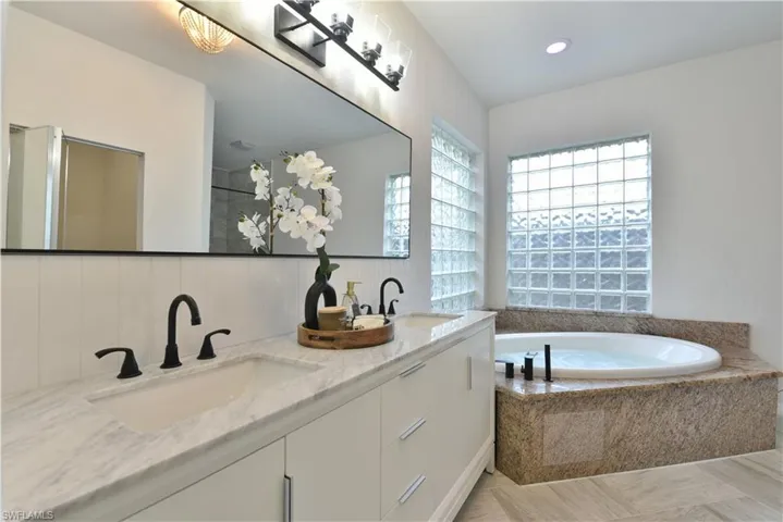 Full bathroom with double vanity, a bath, and a sink