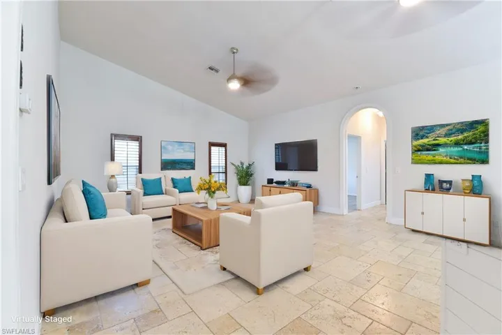 Living area with a ceiling fan, stone tile flooring, visible vents, high vaulted ceiling, and arched walkways
