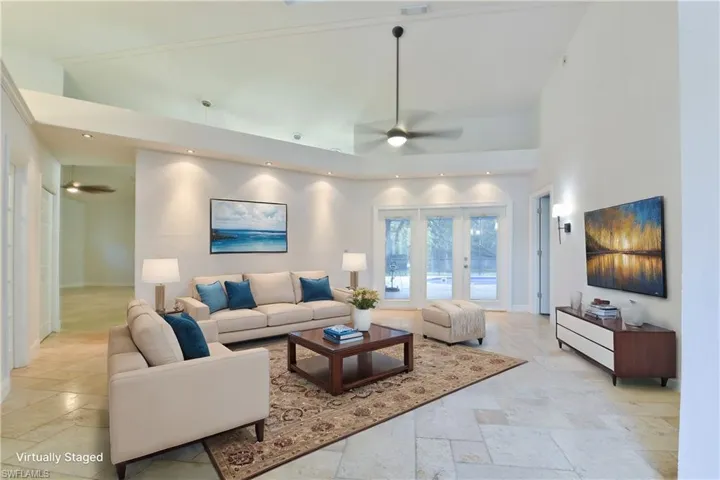 Living area featuring stone tile flooring, ceiling fan, high vaulted ceiling, and recessed lighting