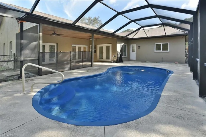 Outdoor pool with a patio area, french doors, ceiling fan, and glass enclosure