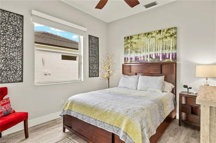 Bedroom featuring a ceiling fan, baseboards, visible vents, and wood finished floors