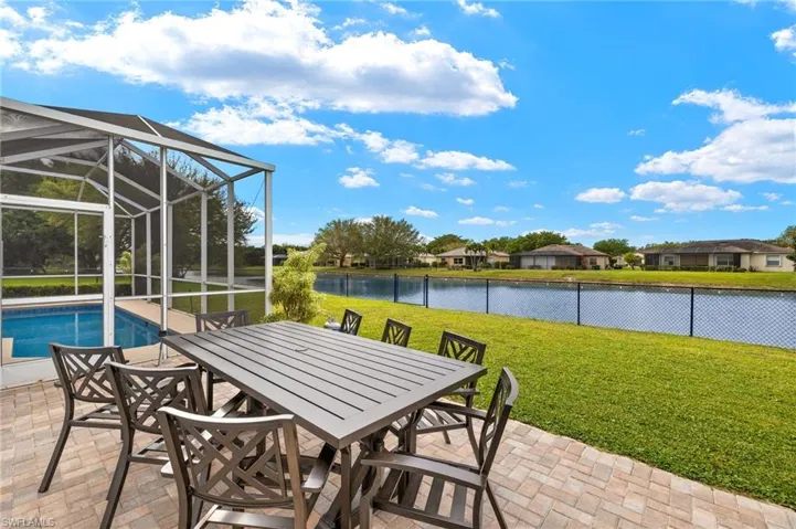 View of patio / terrace featuring a water view, outdoor dining space,  fence, and an outdoor pool.