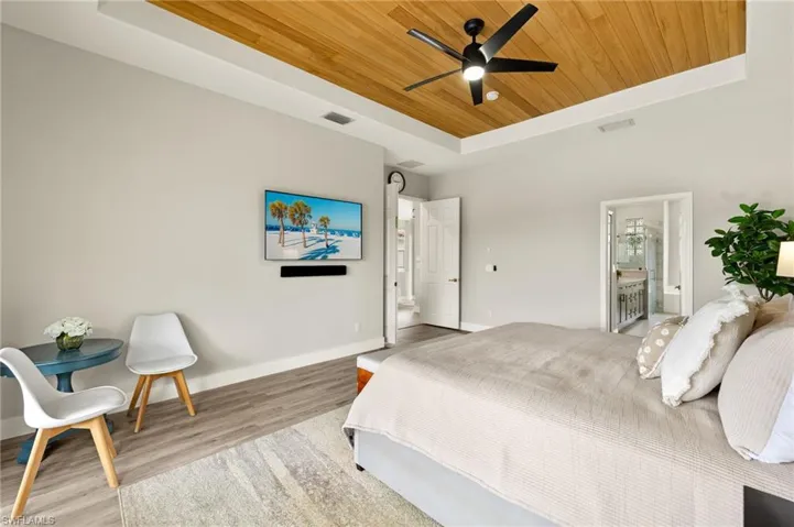 Bedroom featuring a raised ceiling, visible vents, wood ceiling, wood finished floors, and baseboards