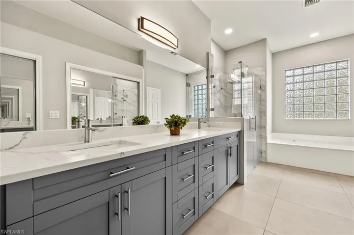Bathroom with a sink, a shower stall with multiple shower heads, and double vanity