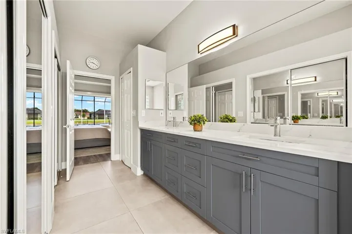 Bathroom with a sink, a shower stall with multiple shower heads, and double vanity