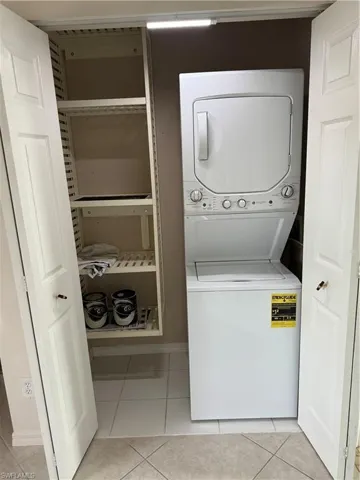 Laundry area featuring stacked washer / dryer and light tile patterned floors
