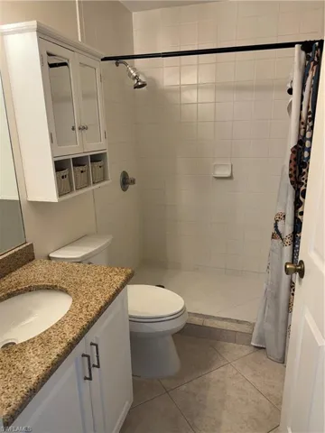 Bathroom featuring a shower with shower curtain, tile patterned flooring, vanity, and toilet