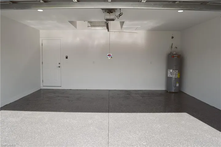 Garage featuring water heater, a garage door opener, and recessed lighting