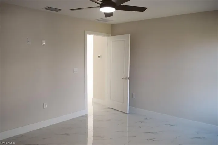 Unfurnished room featuring a ceiling fan, light marble finish floors, and baseboards