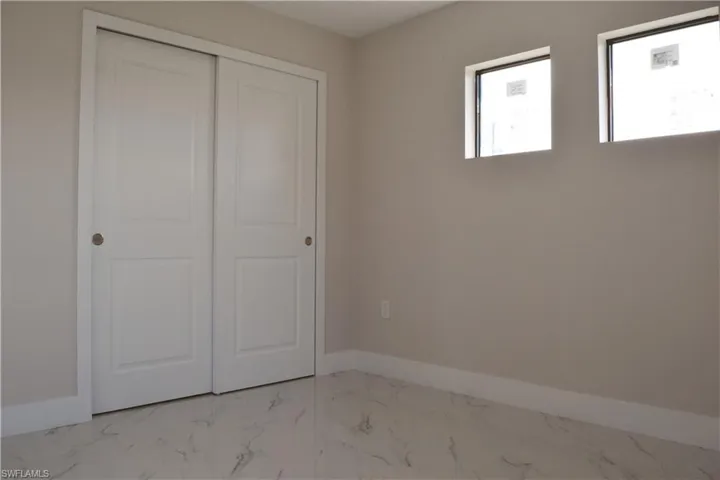 Unfurnished bedroom with marble look tiles, baseboards, and a closet
