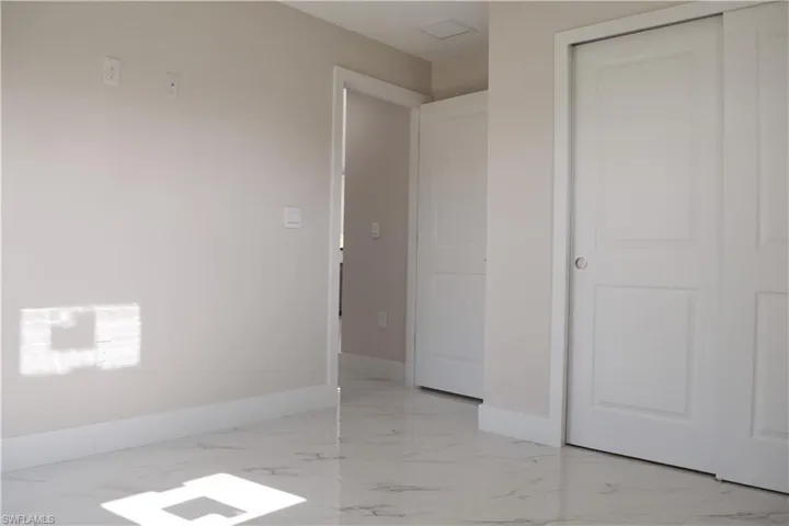 Unfurnished bedroom featuring light marble finish flooring, baseboards, and a closet