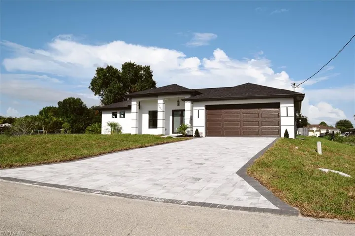 Prairie-style house featuring stucco siding, a garage, decorative driveway, and a front lawn