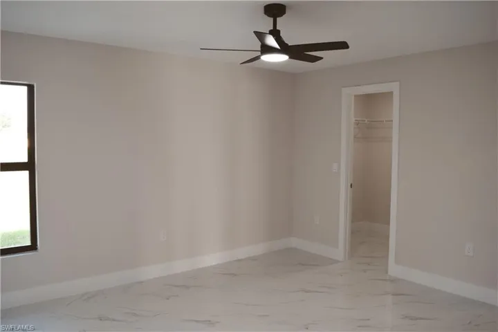 Unfurnished bedroom featuring light marble finish floors and baseboards
