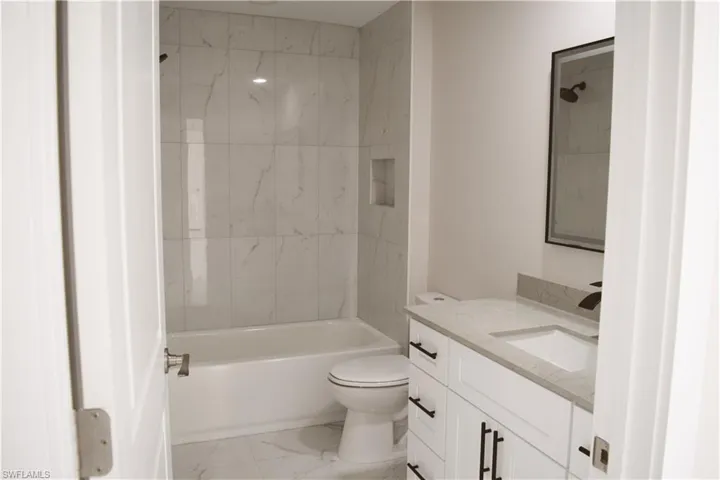 Full bathroom with vanity, marble finish floors, toilet, and  shower combination
