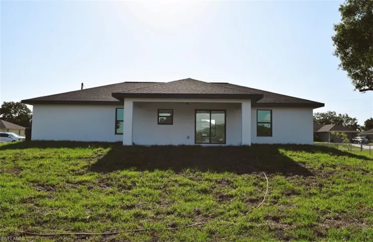 Back of house featuring stucco siding, a lawn, and a shingled roof