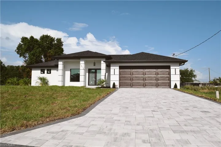 Prairie-style house featuring decorative driveway, stucco siding, a front lawn, an attached garage, and a shingled roof