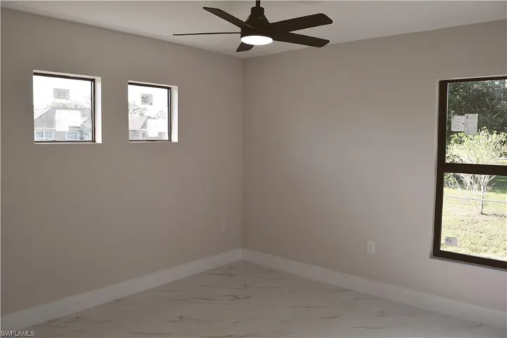 Unfurnished room with marble finish floors, baseboards, and ceiling fan