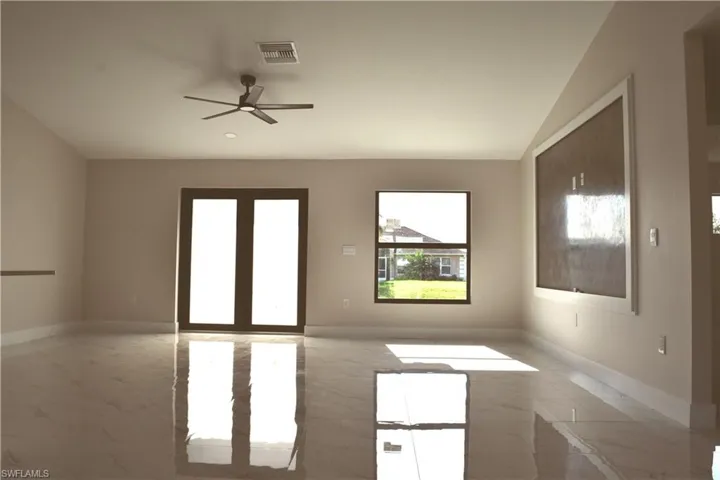 Spare room with light marble finish floors, ceiling fan, baseboards, and vaulted ceiling