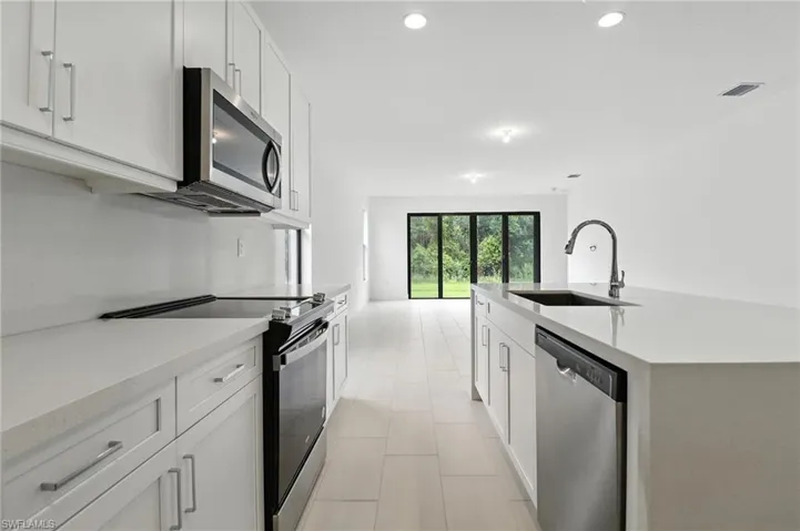 Kitchen with appliances with stainless steel finishes, light countertops, recessed lighting, light tile patterned floors, and a kitchen island with sink