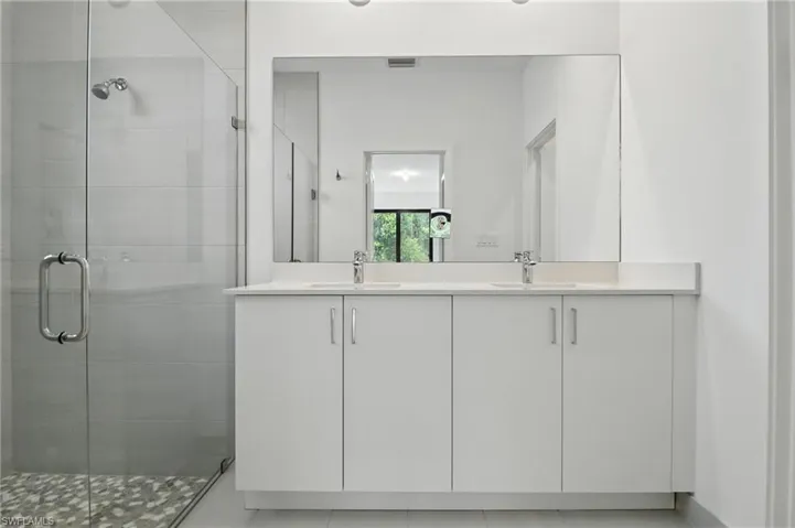 Full bathroom with double vanity and a stall shower