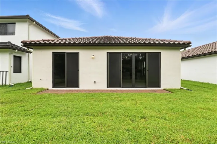 Rear view of house with stucco siding and a yard