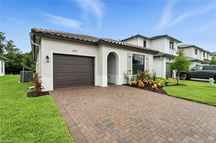 Mediterranean / spanish-style home with decorative driveway, stucco siding, a garage, a front yard, and a tile roof